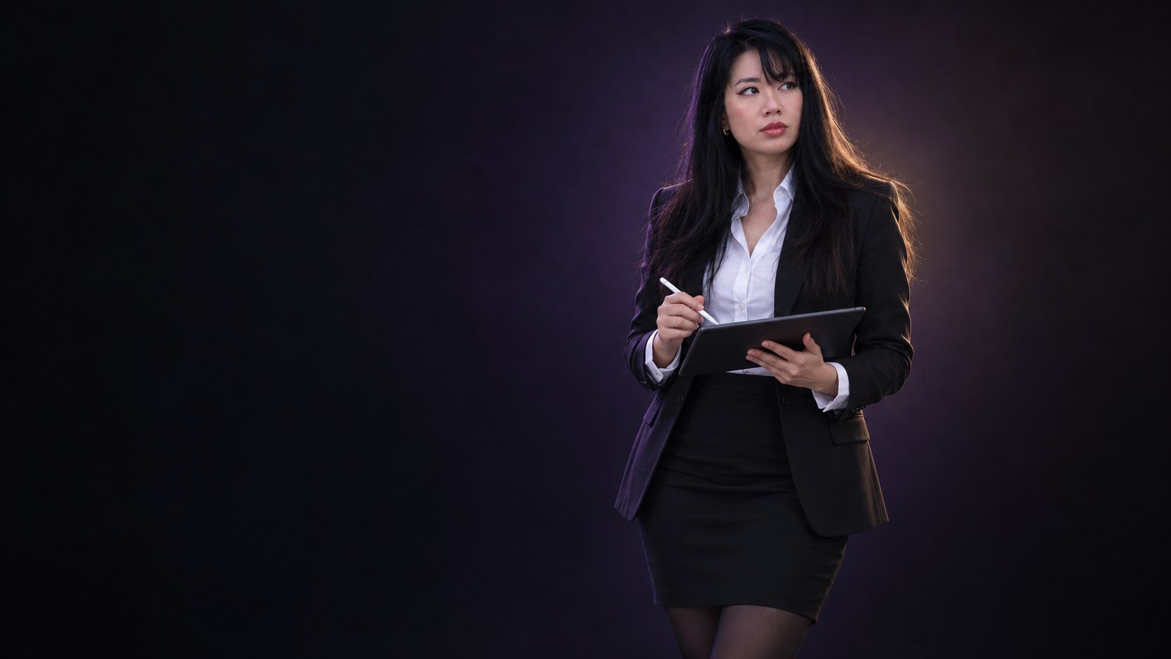 Cathy en tailleur, tablette et stylet en main, le regard tourné vers le côté.
